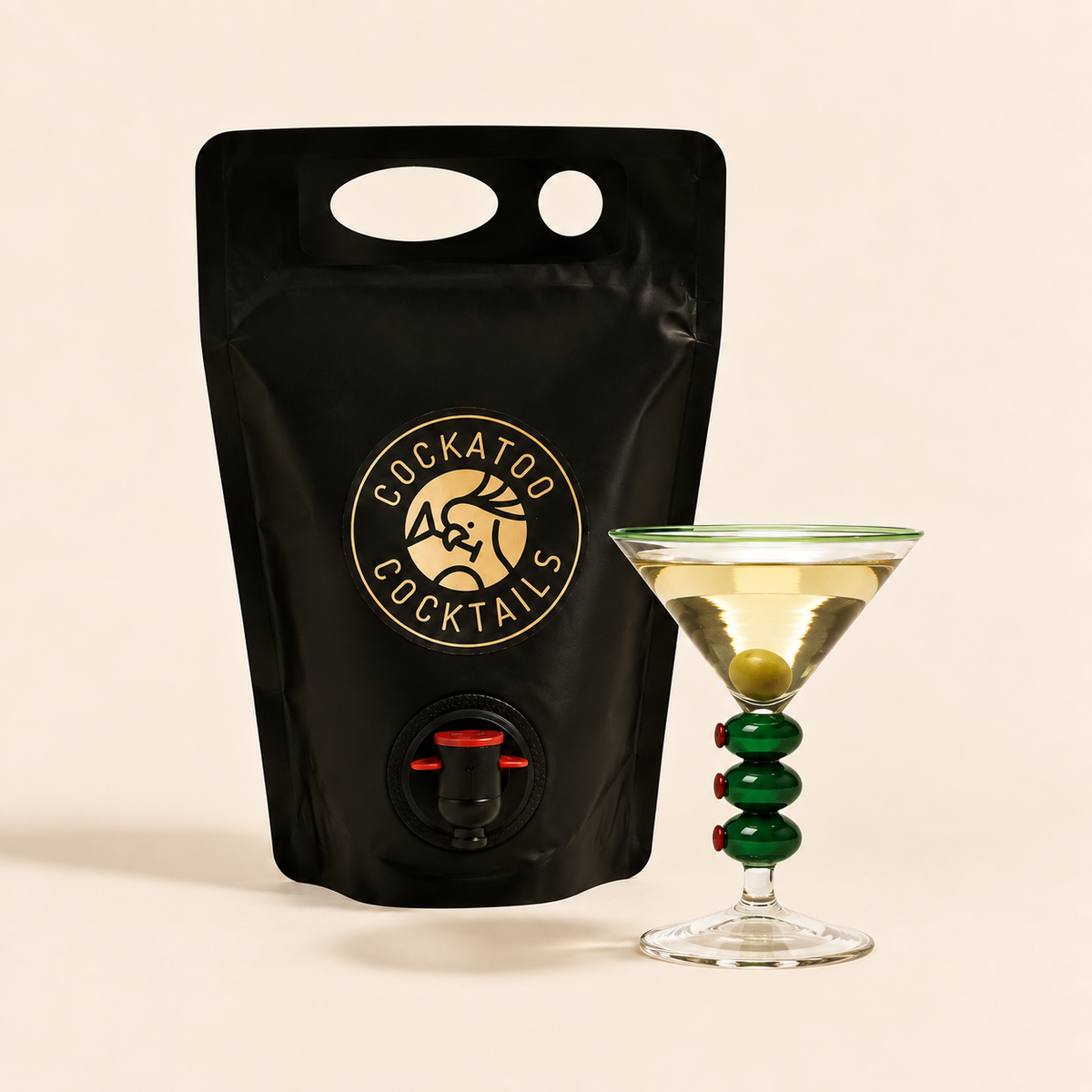 A black stand-up pouch with a handle and a visible Cockatoo Cocktails logo and spout, shown next to a dirty martini cocktail.
